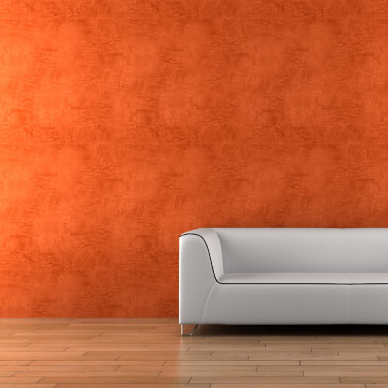 white sofa and vase with dry wood in front of orange wall