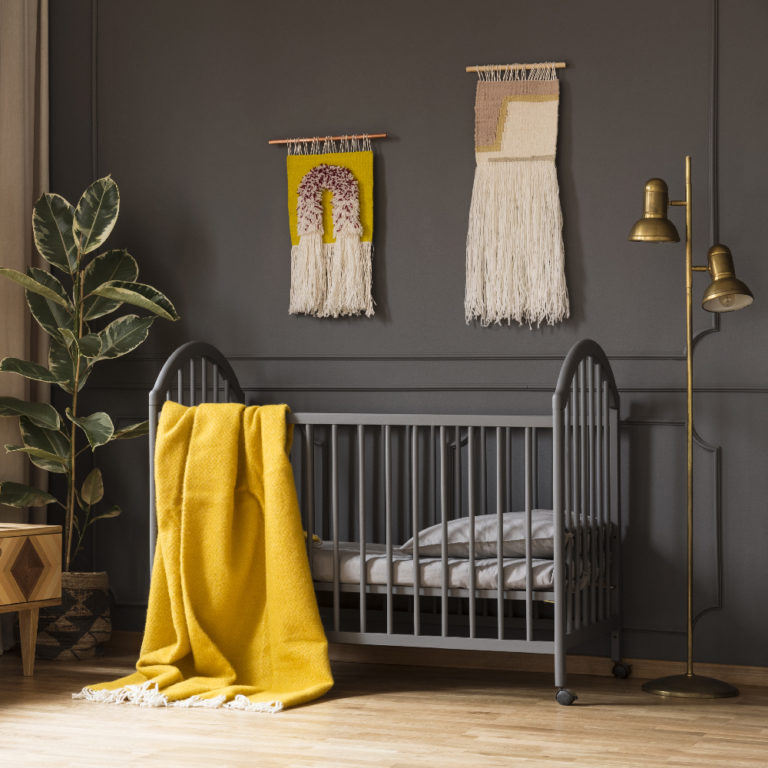 Real photo of a cot with a yellow blanket standing between a low